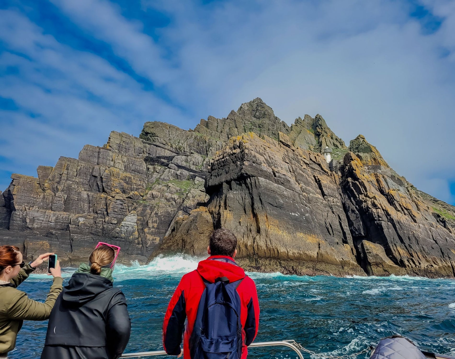 Three people on a boat taking photos of the Skellig Islands