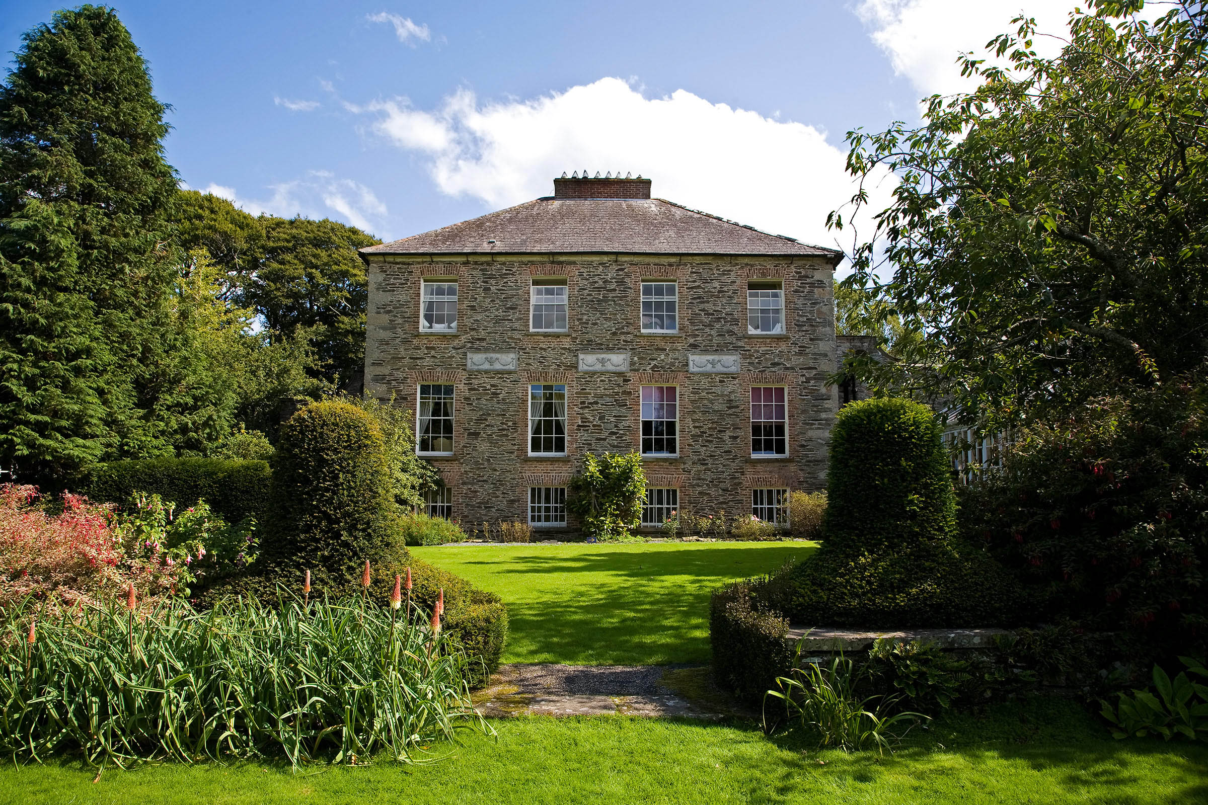 The exterior of a house at Kilmokea Country Manor Gardens with trees on either side.