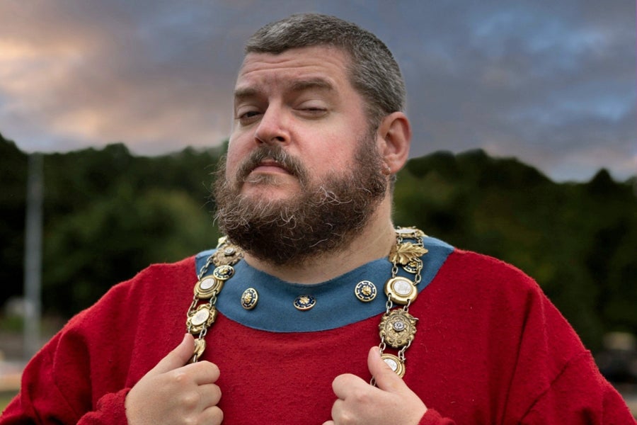 A tour guide in a red costume with decorative chain