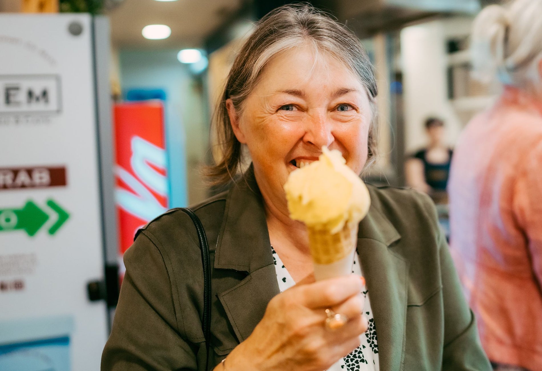 Lady holding an ice cream and cone while smiling at the camera