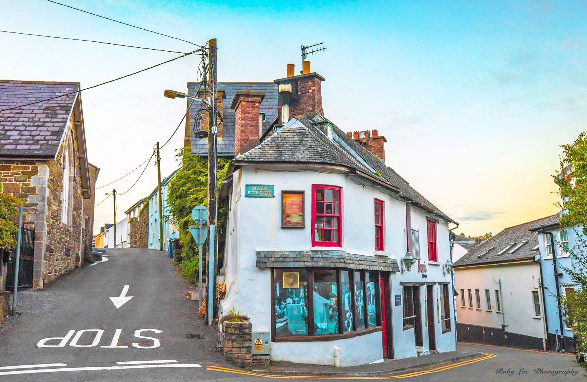 Historic Stroll in Old Kinsale view of an old corner shop painted white with red framed windows