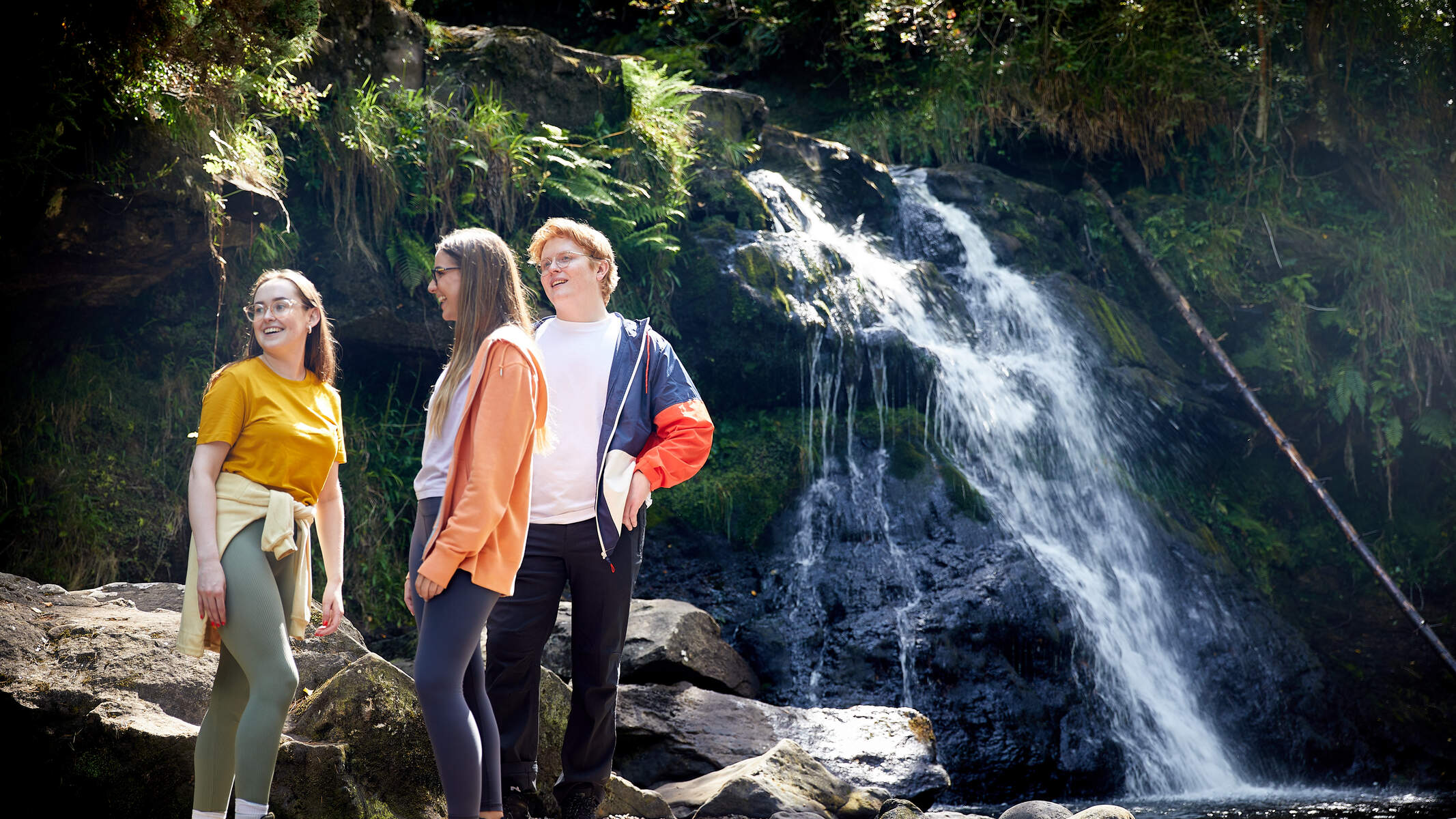 Friends standing beside a waterfall on the Glenbarrow Eco Walk.