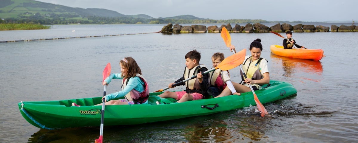 Three children and an adult kayaking on a lake