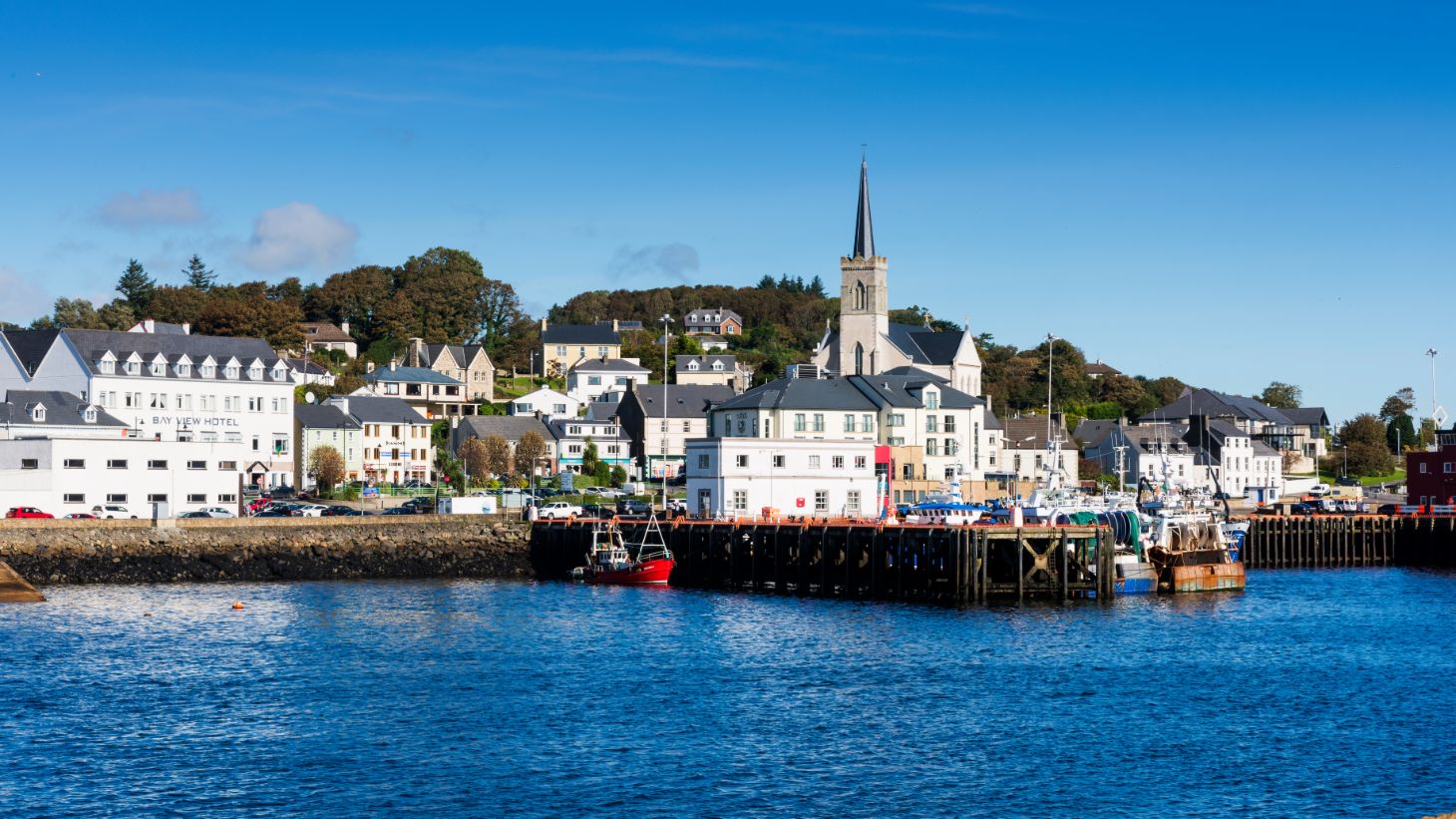 An image of boats by the pier in Killybegs against a backdrop of houses and a church