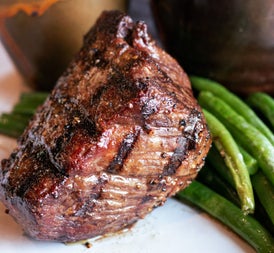 A cooked steak with green beans