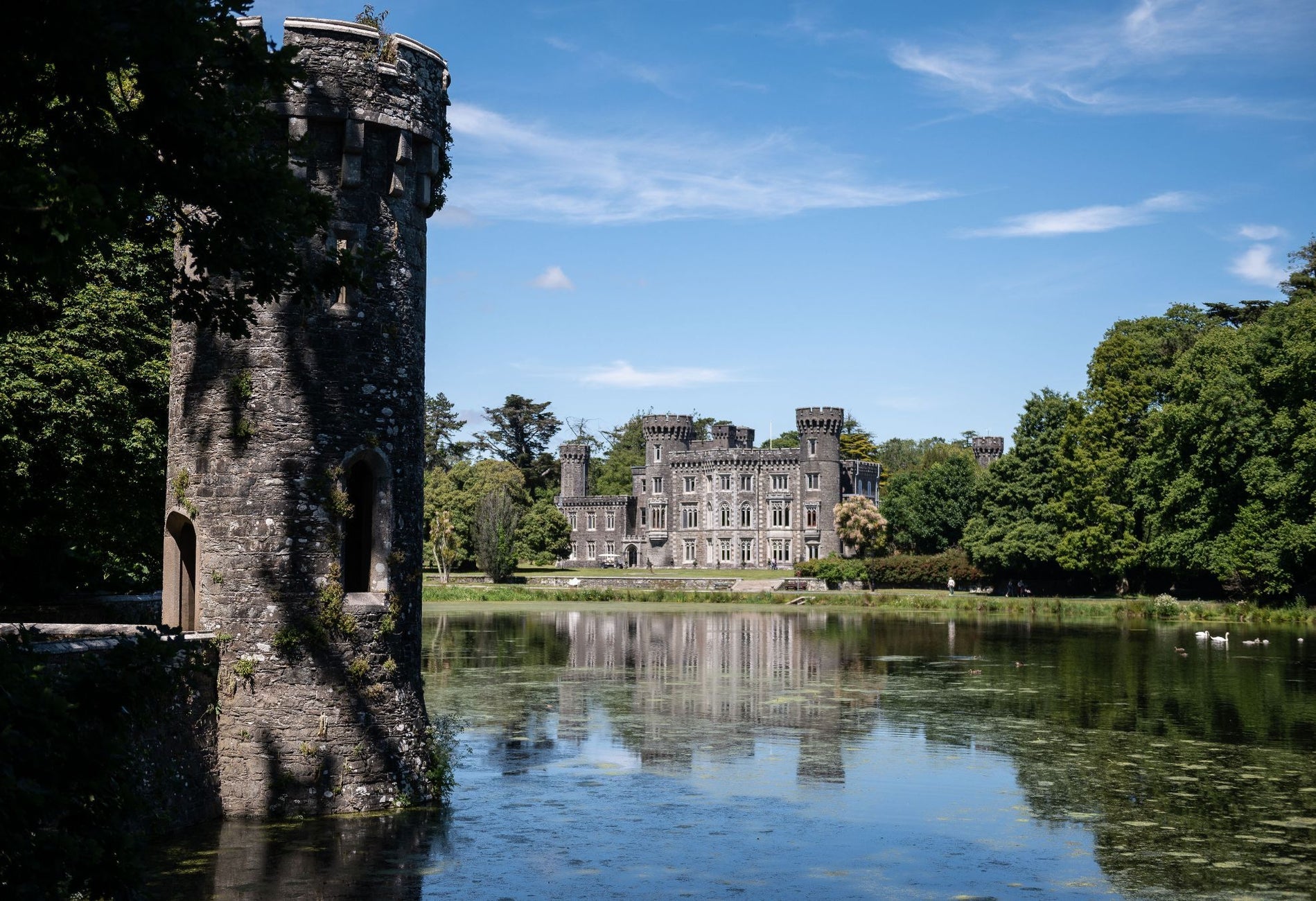 Johnstown Castle reflected in the lake surrounded by trees on the estate grounds