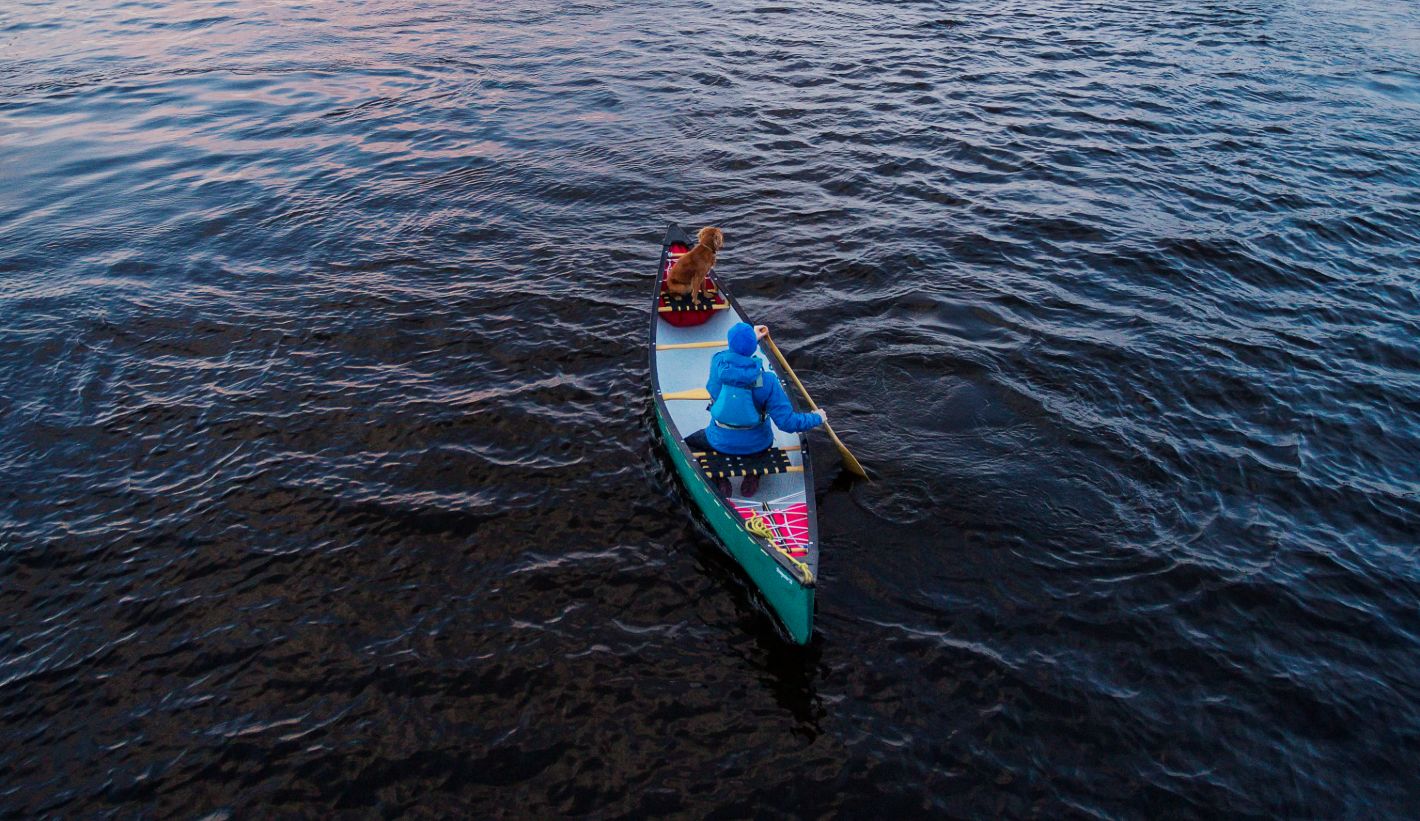 A woman paddling with a dog on Lough Derg.