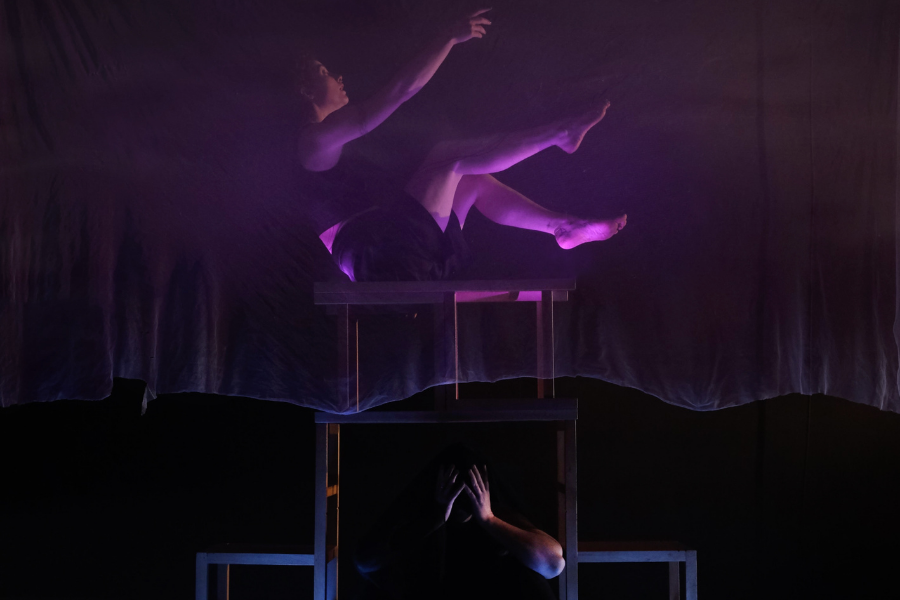 Darkly lit photo of person performing in contemporary circus