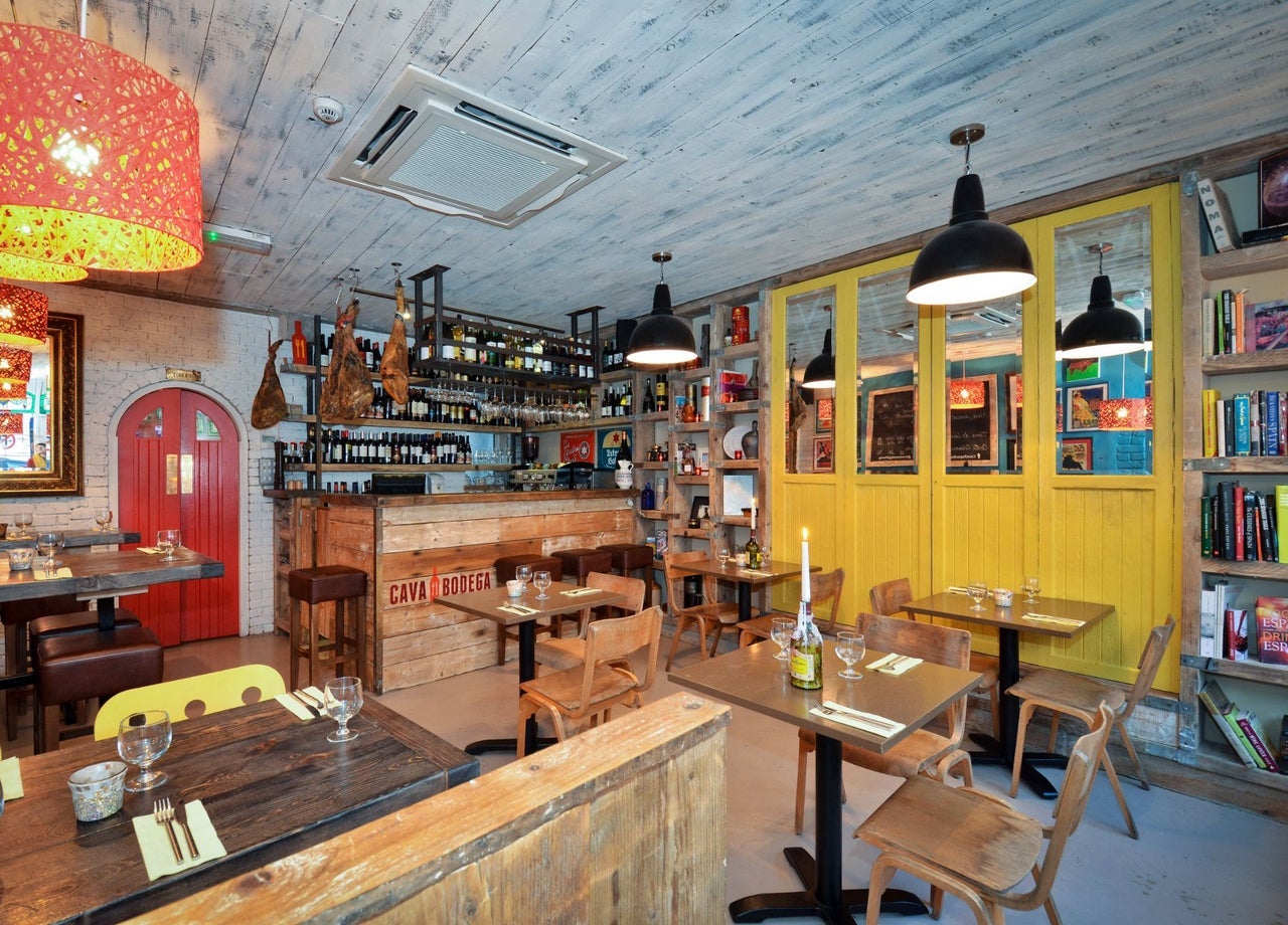 The interior of Cava Bodega restaurant featuring warm wooden furnishings and shelves of wine and books