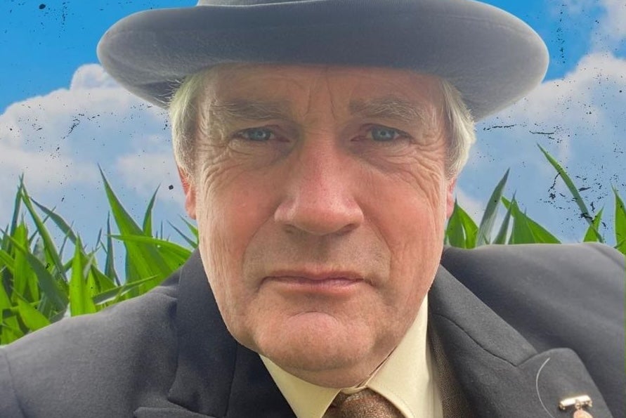 A man in a grey hat and jacket looking intent.