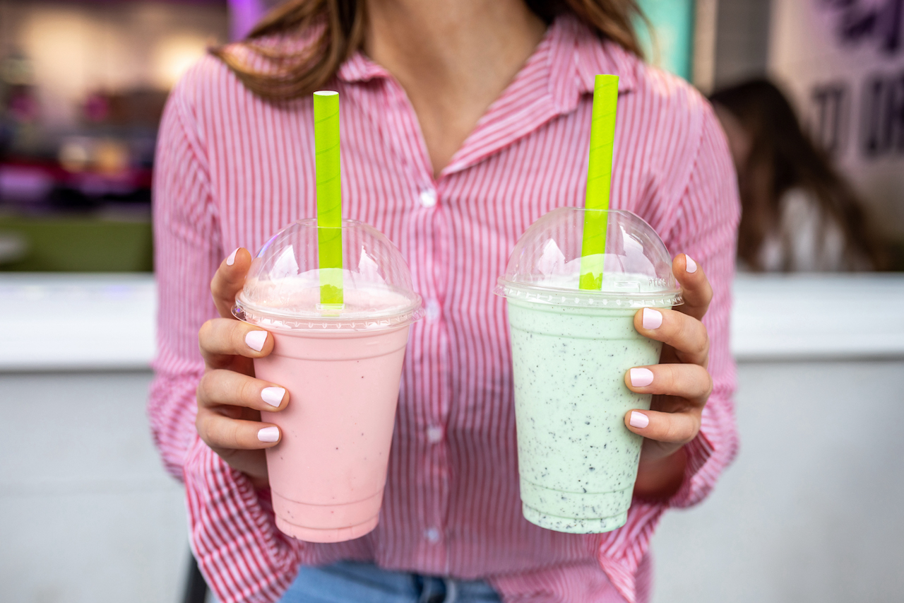 A lady holding two milk shakes from Ginos Gelato