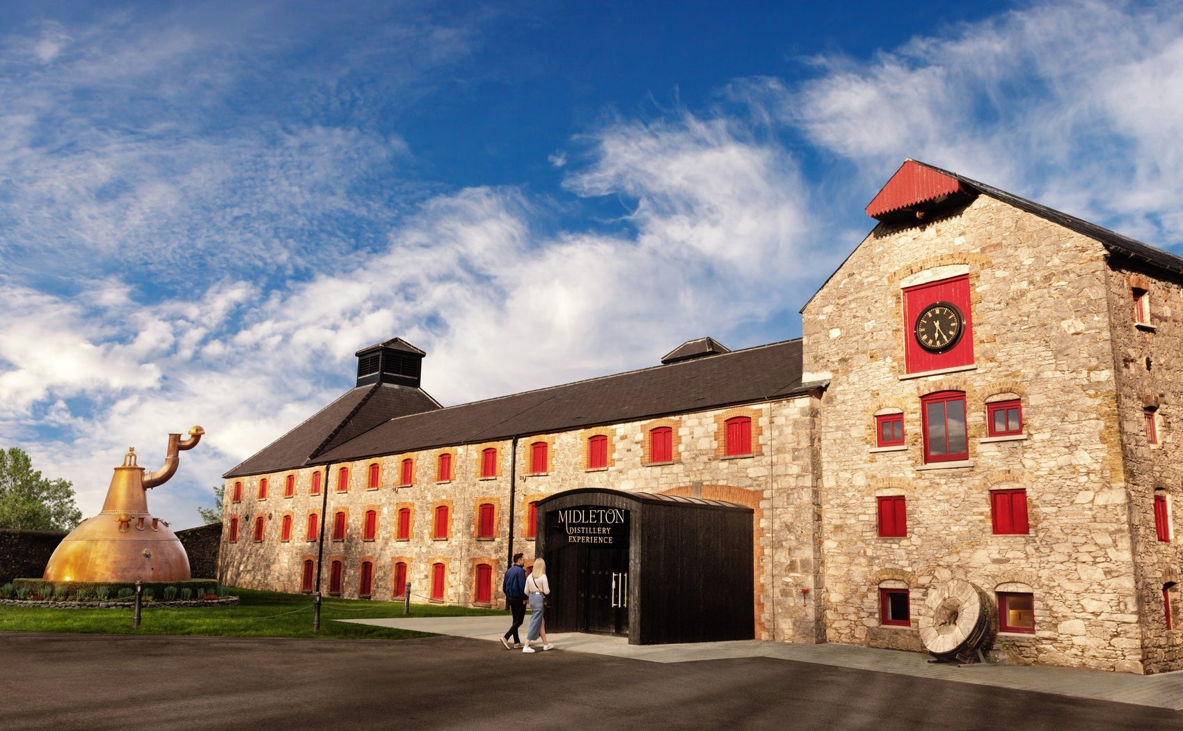 A large building with exterior walls of brick and a replica of a whiskey still outside