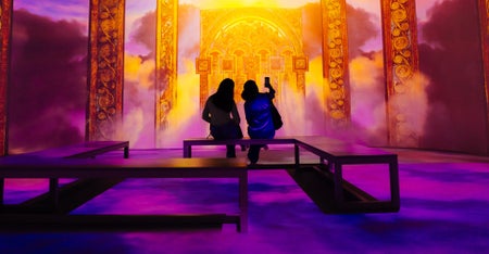 Two people enjoying The Book of Kells 360 experience which is a journey in light and sound