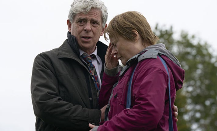 A upset woman being comforted by a man outdoors.