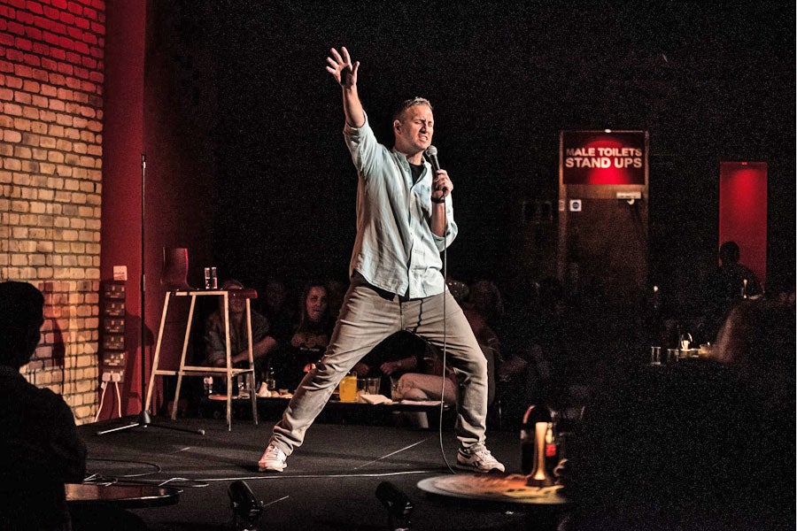 A comedian standing on stage in mid performance