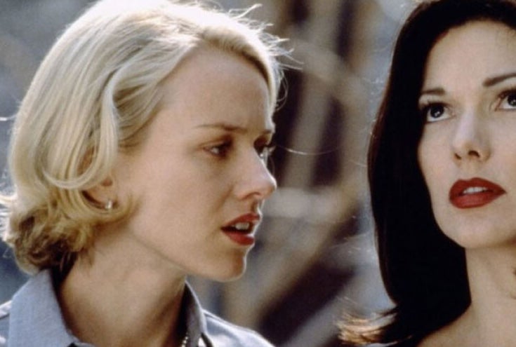 A woman is talking to another woman close beside her who is looking upwards.