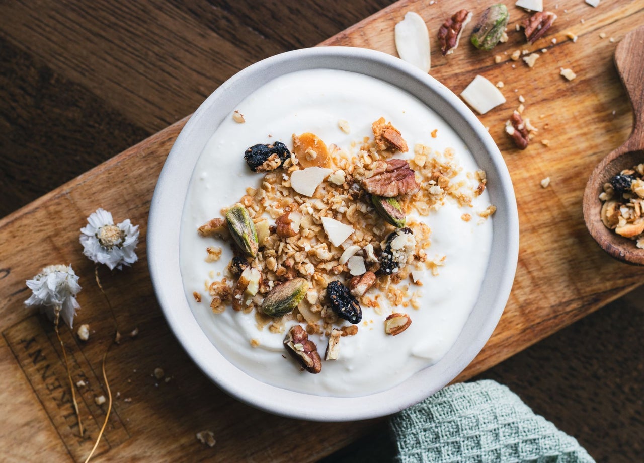 A bowl of creamy yoghurt topped with crunchy granola and dried fruits