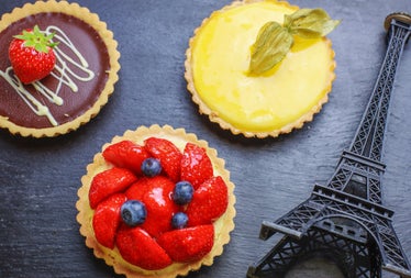 Three tartlets with fruit on a table with a model of the Eiffel Tower beside them