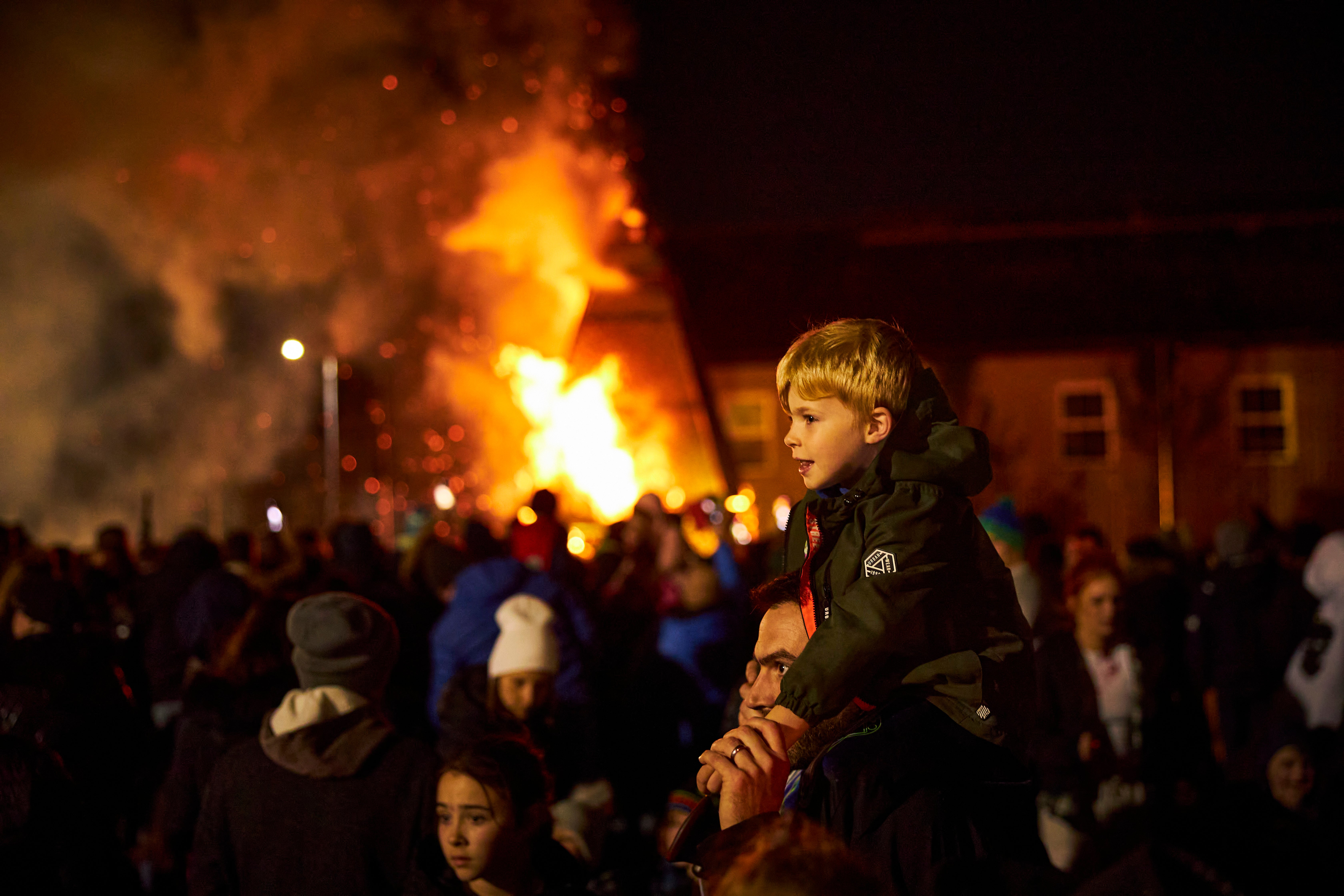 Boy sitting on his father's shoulders to watch the Samhain Procession in Longford.