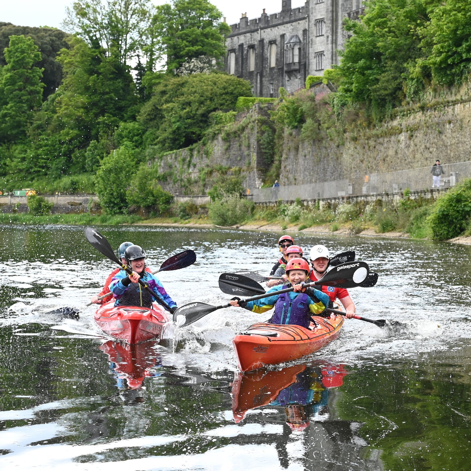 A group of people on the River Nore beneath Kilkenny Castle in double kayaks