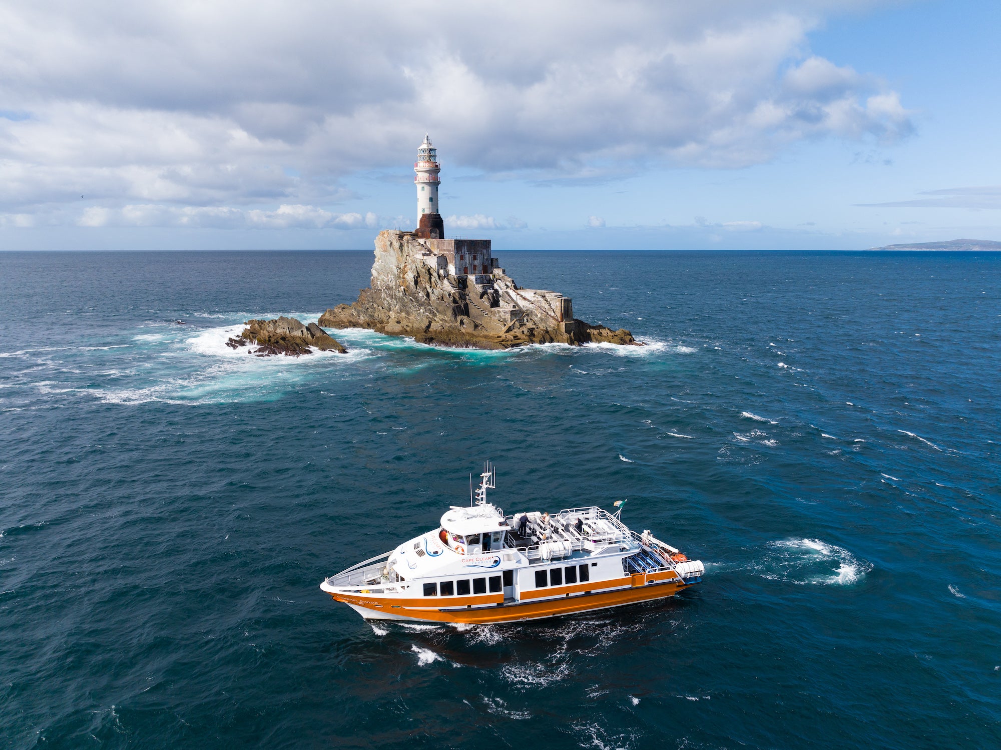 A boat sailing past Fastnet Lighthouse in West Cork