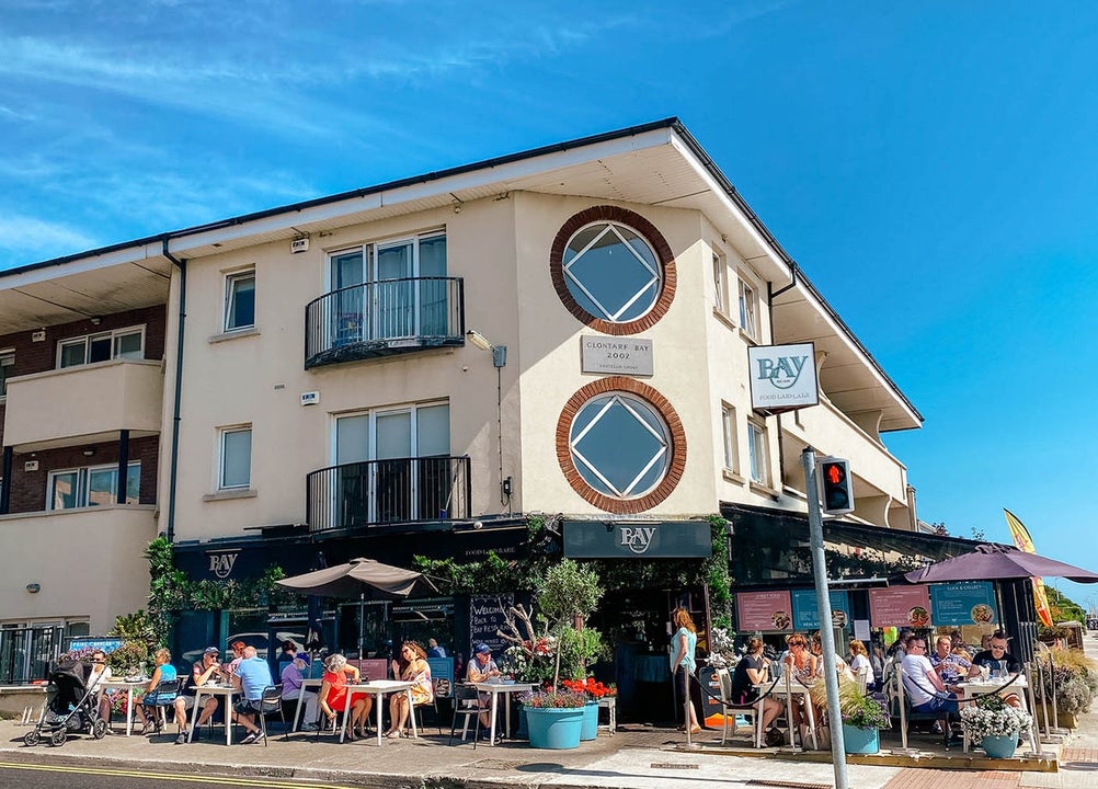 Exterior view of the Bay Restaurant with people dining al fresco