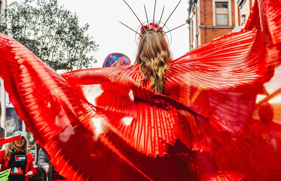 Brigit 2026: Dublin City Celebrating Women - rear view of woman in parade in wide red outfit.
