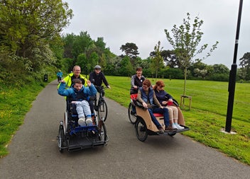 Two people peddling trishaws while passengers sit in each one