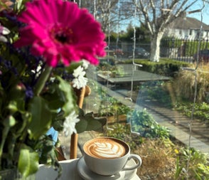 A cup of coffee on a table with a pink flower