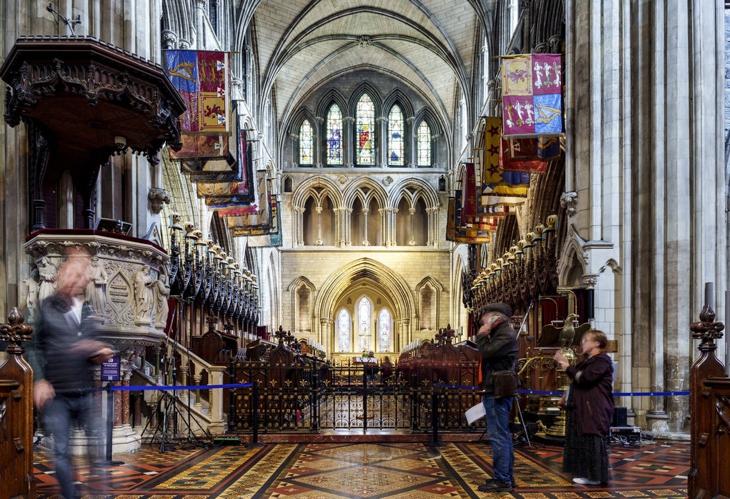 Nave of a church with banners on either side and stain glass windows in the background
