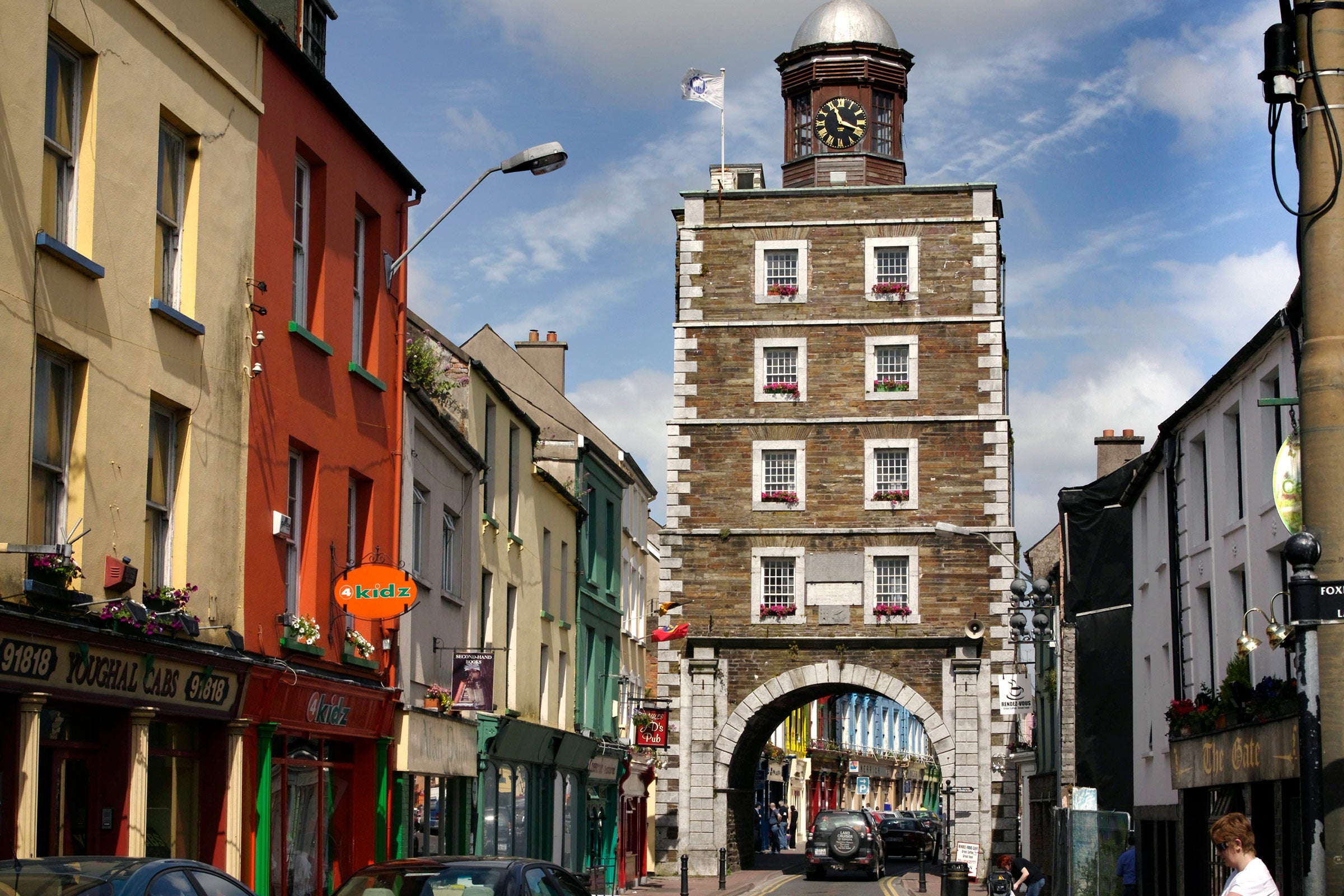 Youghal Clock Gate Tower, shop fronts and cars on a busy street
