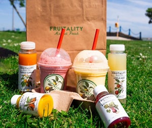 A selection of bottles and containers with colourful fruit juices displayed on grass