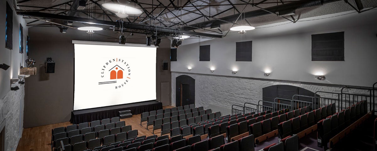A theatre with tiered seating facing a cinema screen
