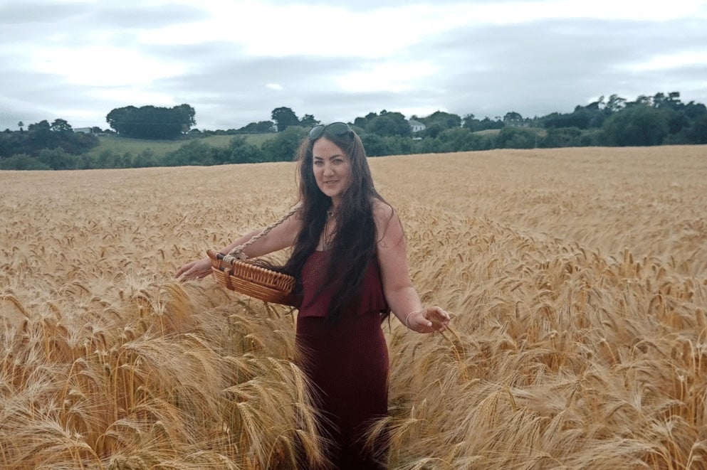 A woman standing in the middle of a field of ripe corn.