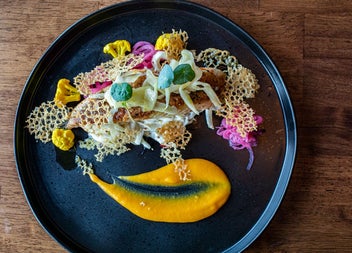 A piece of fish topped with shaved vegetables and crisp style garnishes