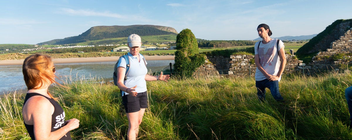 A couple standing either side of a guide on a coastal walking tour
