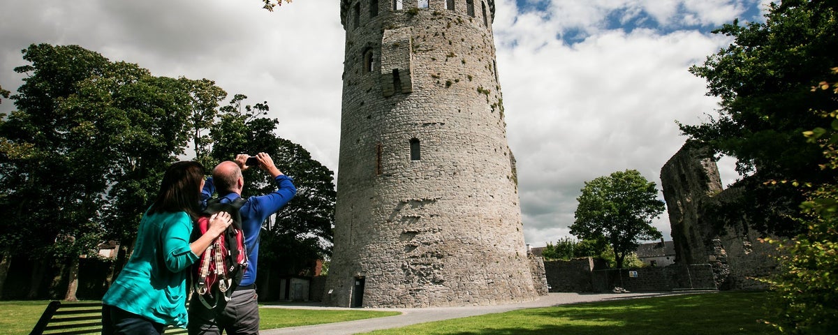 Two people pointing their camera up at a tower