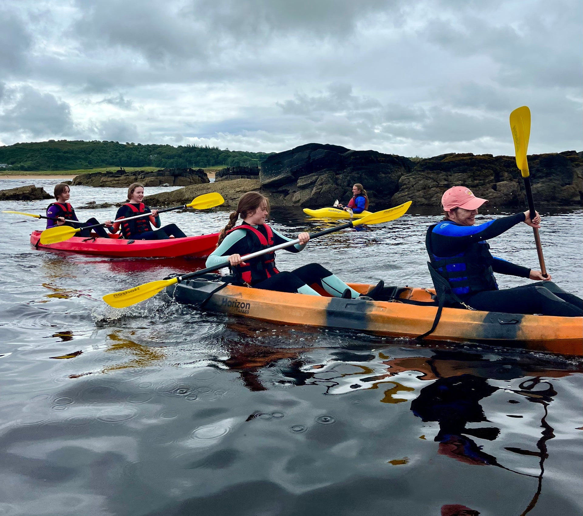 Three kayaks with kayakers and guide on water