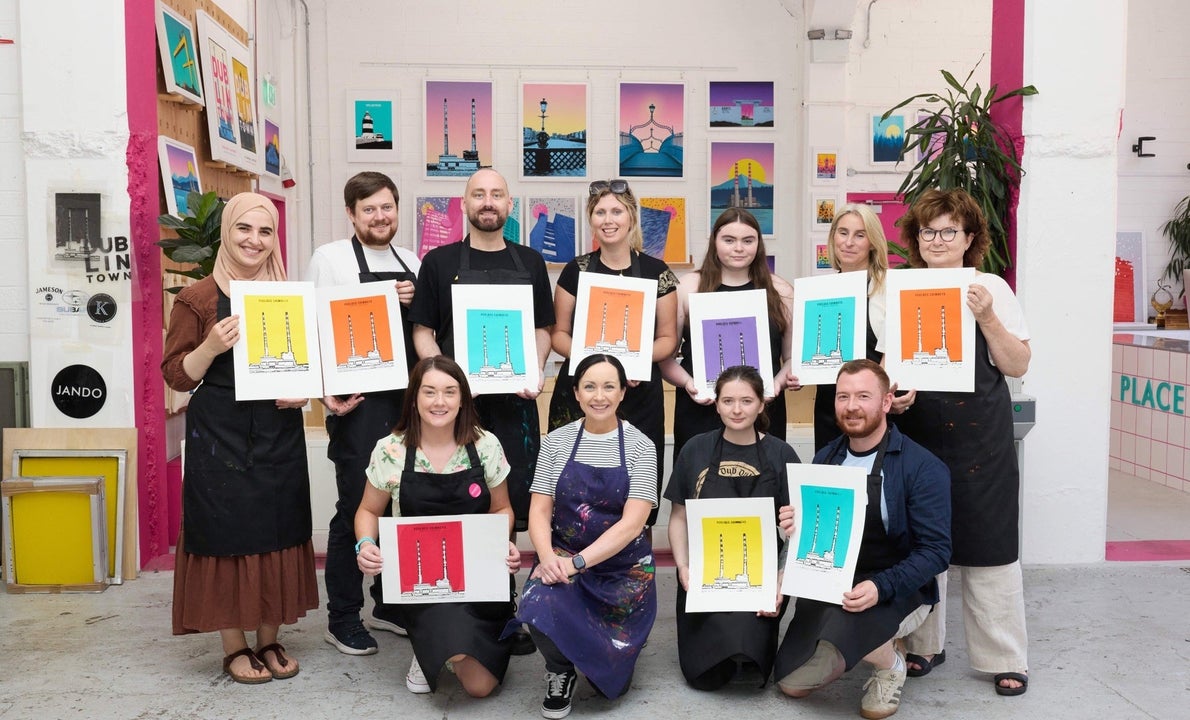 Group of people holding colourful prints posing for a picture