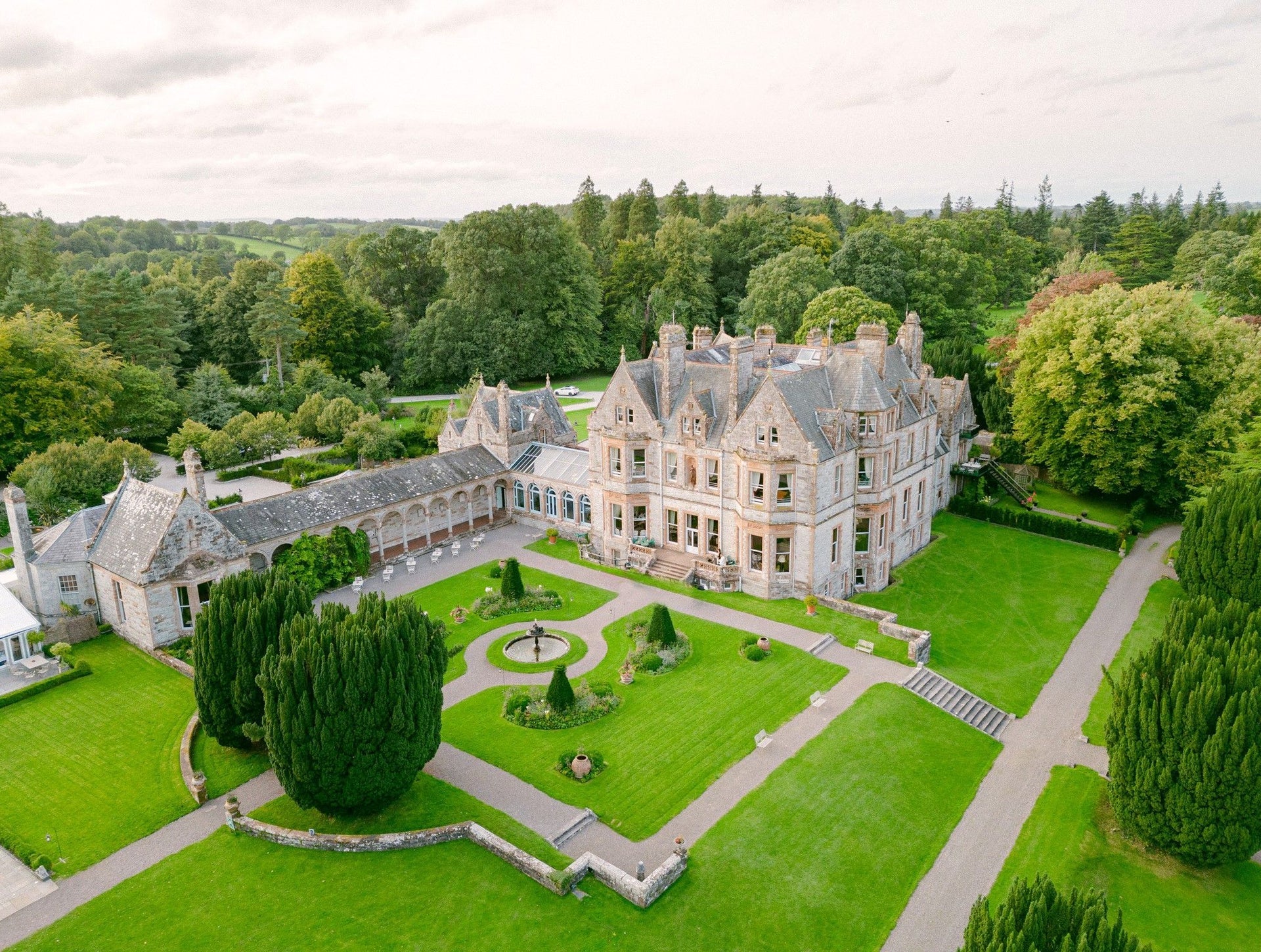Aerial view of a large country estate house with a formal lawn area