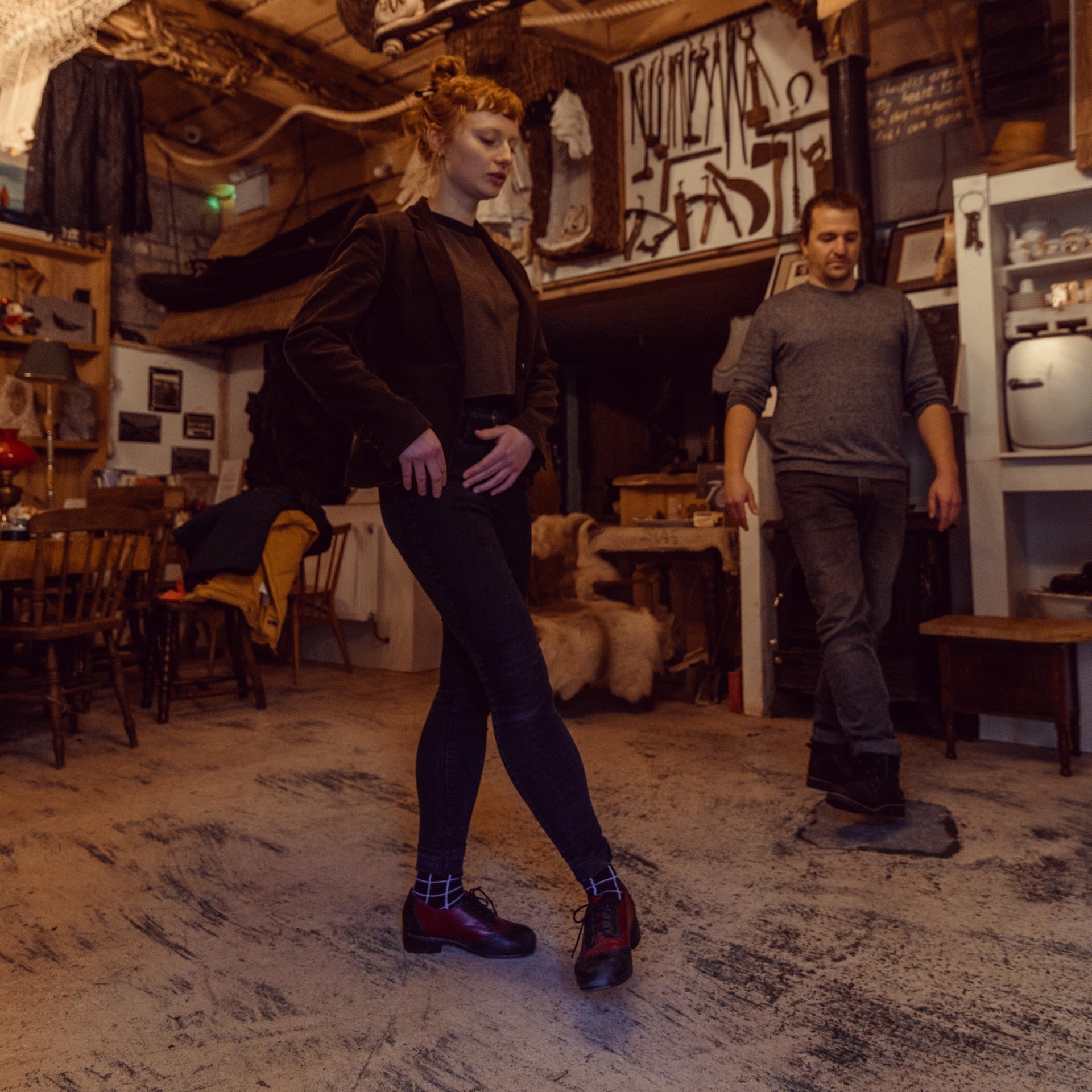 Two people practising Irish dancing in a room with a wooden floor and table and chairs in the background
