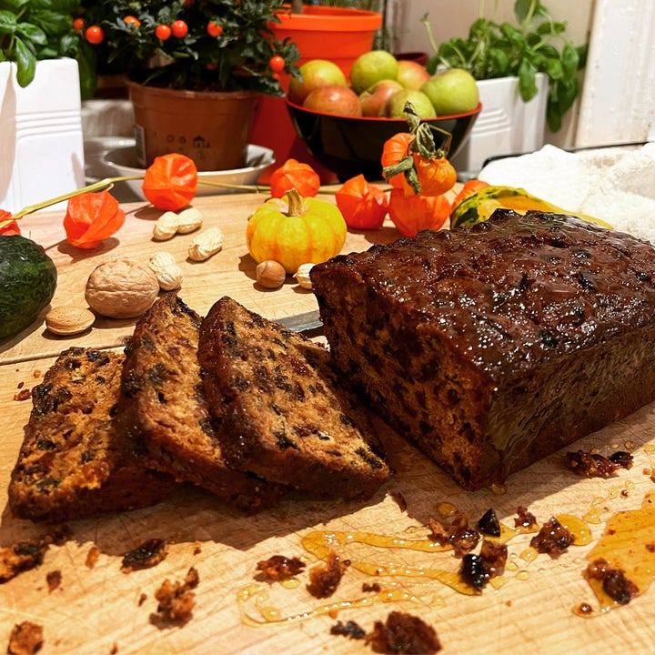 A fruit loaf with some slices cut on a wooden chopping board