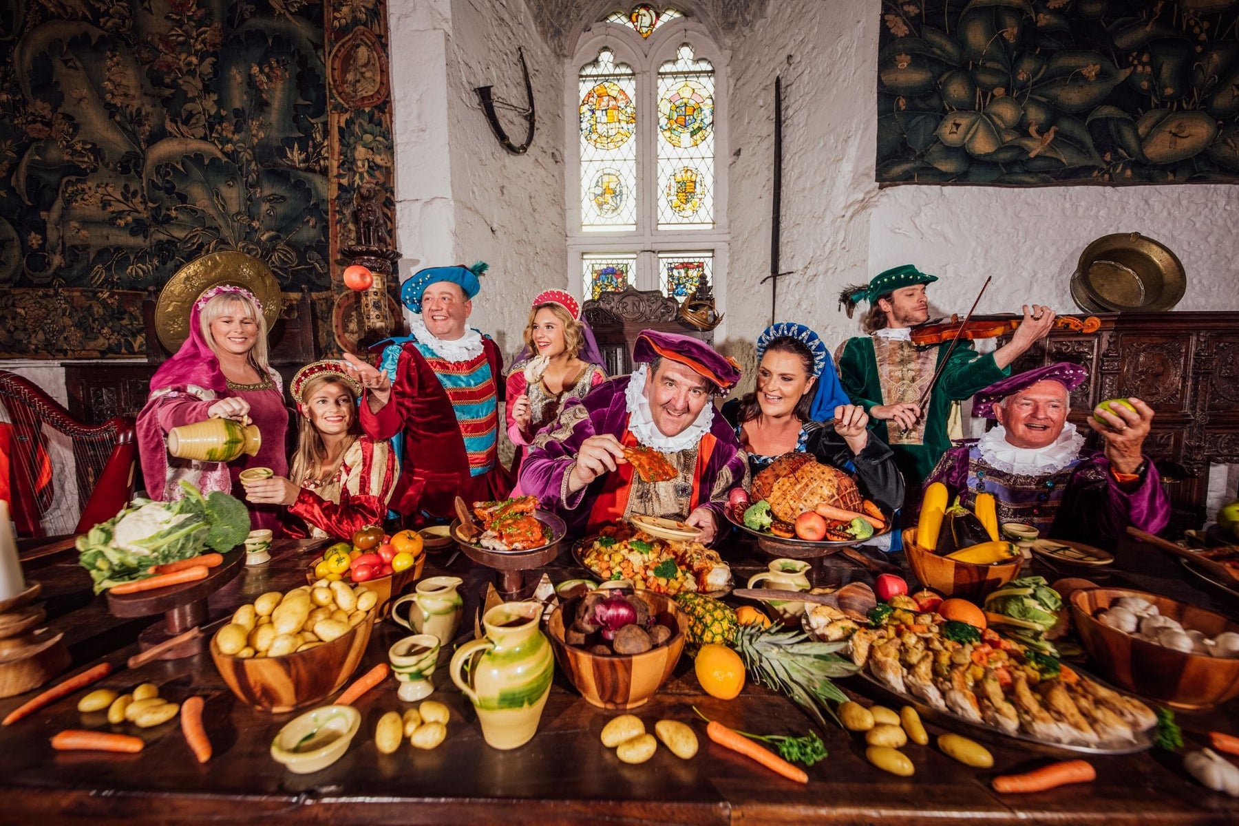 People in medieval costume posing at a table laid out with food and drink
