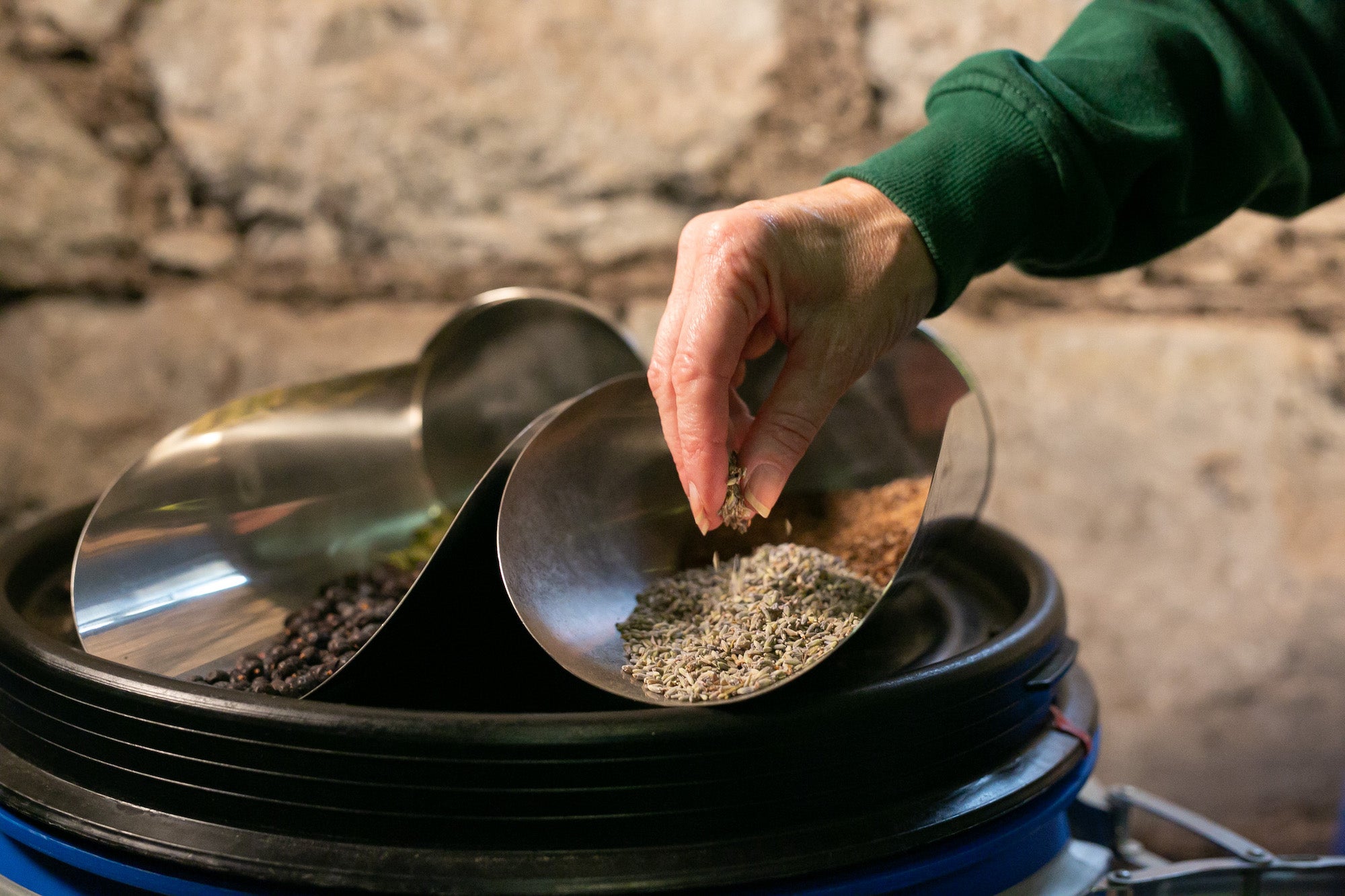 The image shows a hand picking up grains from a silver shovel.