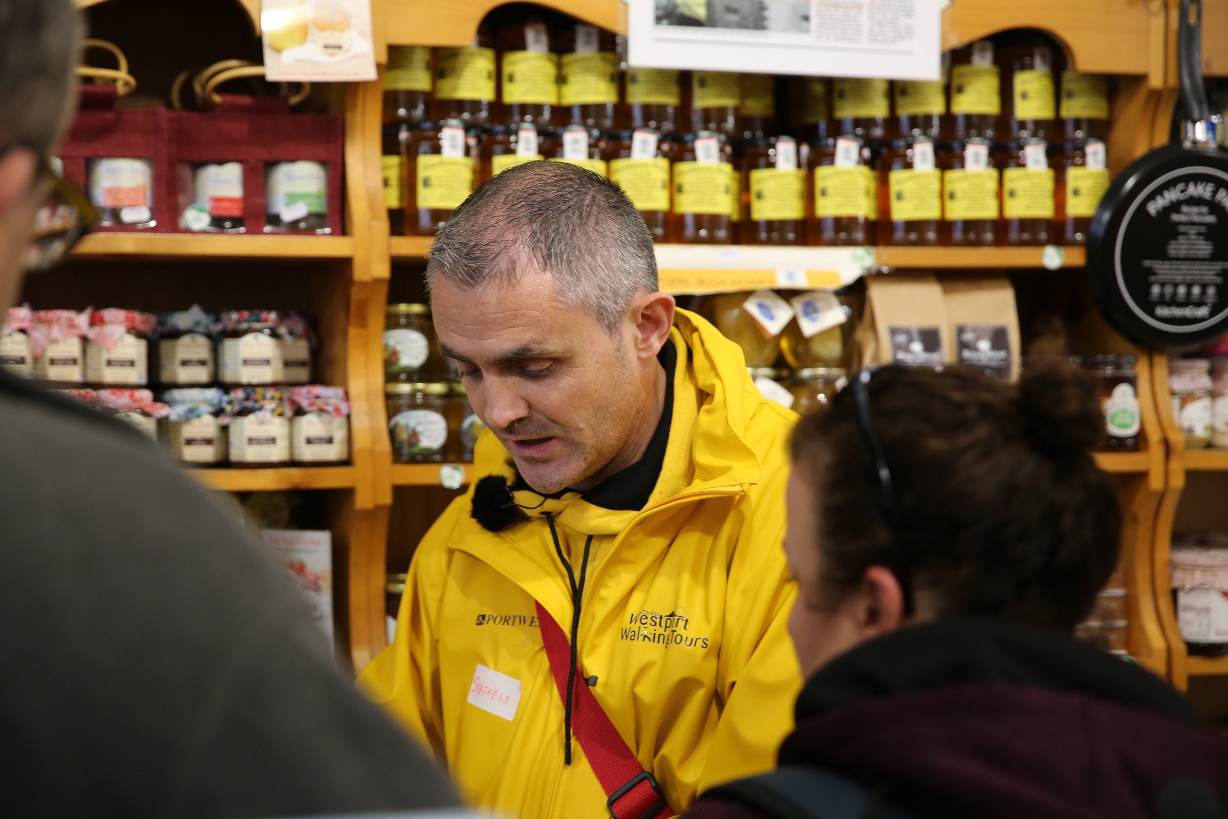 A tour guide discusses a food item with two people standing in foreground