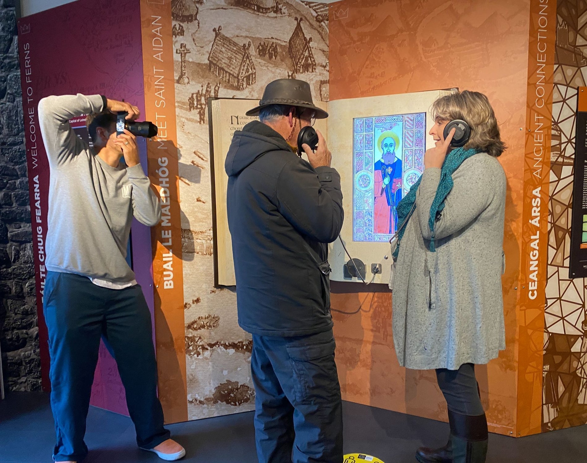Visitors being photographed using headphones and interactive displays inside a museum