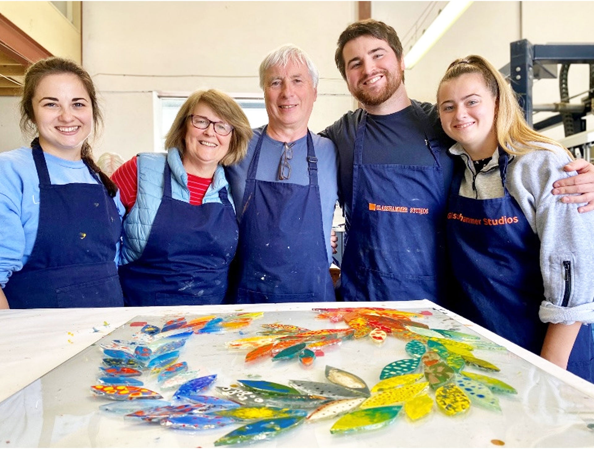 Glasshammer Studios view of five people next to their colourful painted glass project