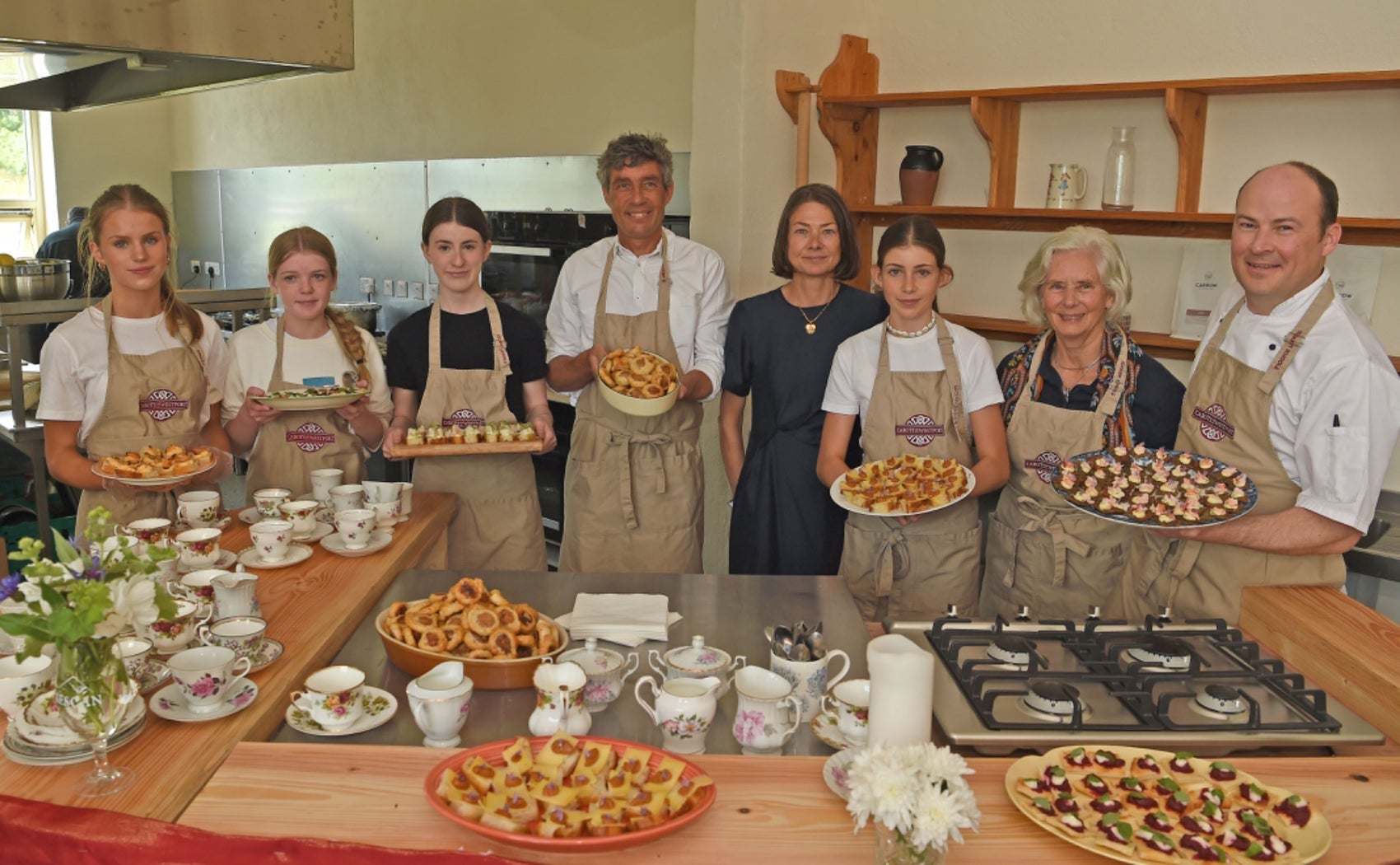 People holding full platters while standing in front of a counter with other baked goods on display
