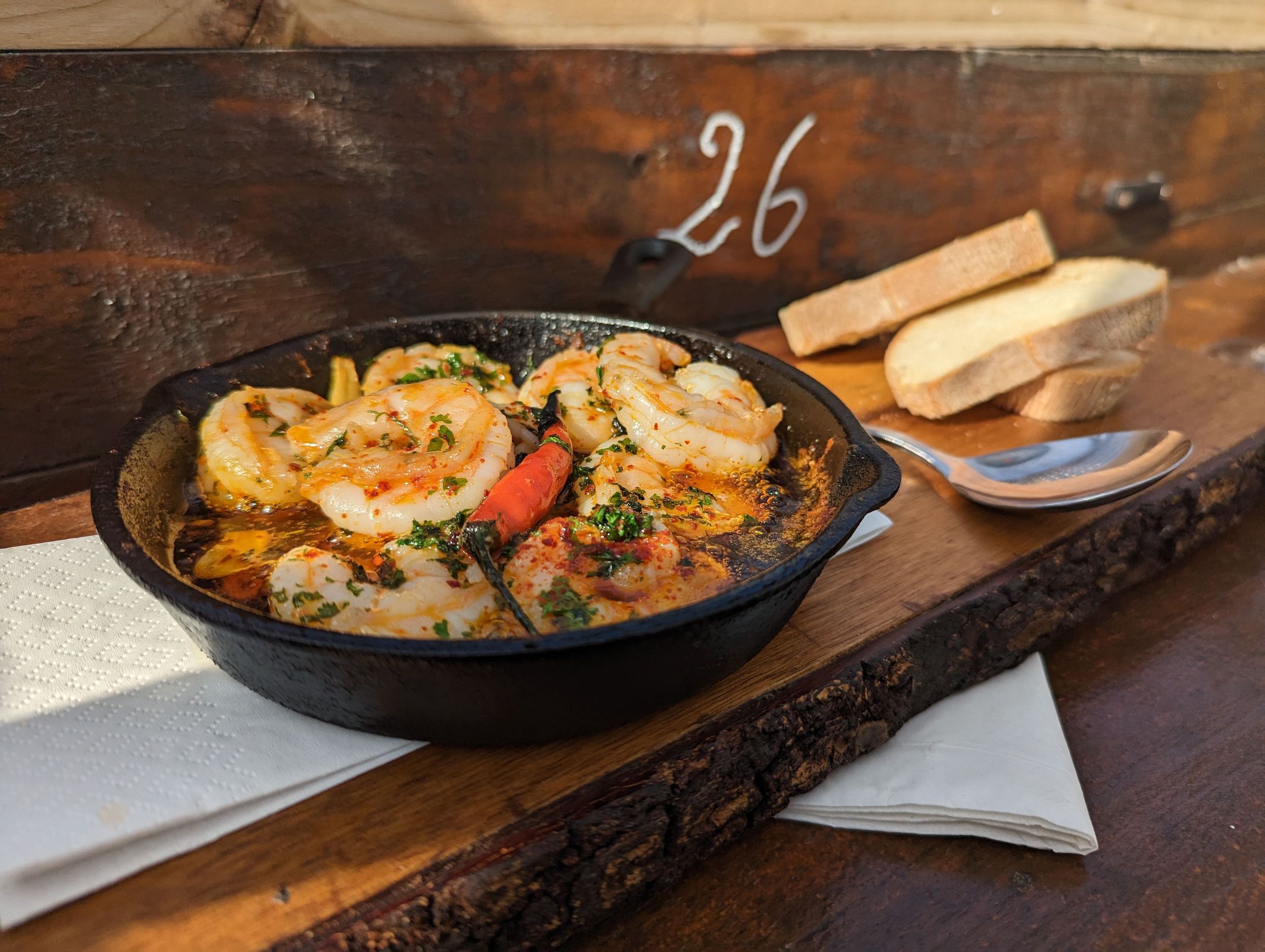A dish of prawn pil pil with two slices of bread.