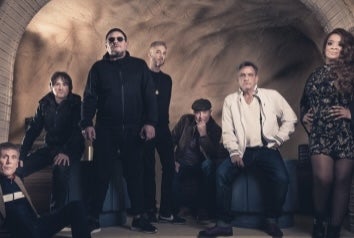 A group of people standing and sitting under a cellar brick arch.